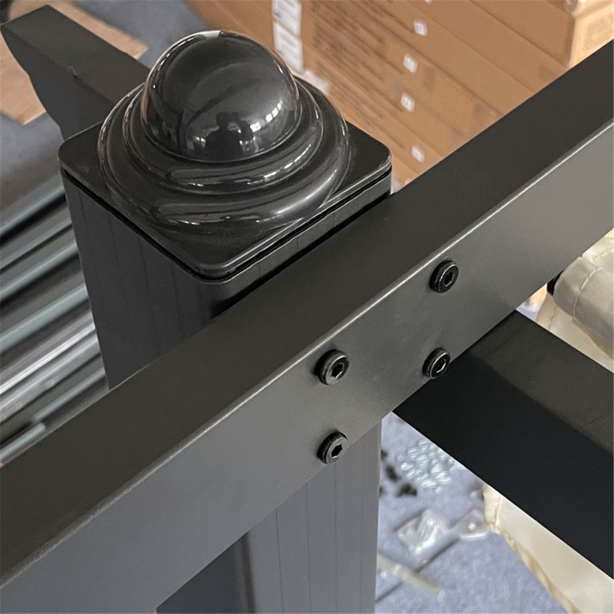 Black metal bracket with a spherical component on a blurred warehouse background
