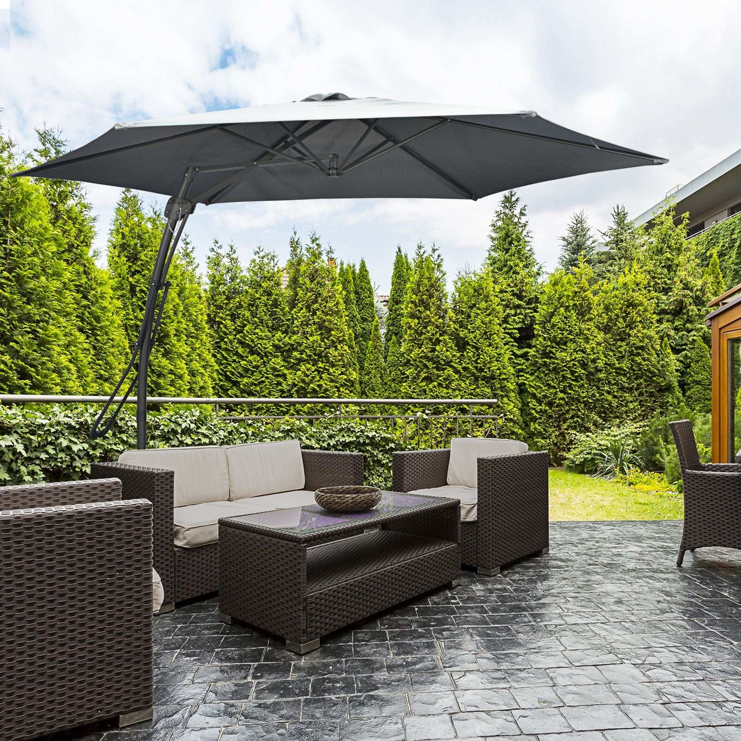 Outdoor patio set with a large umbrella on a stone patio, surrounded by greenery.