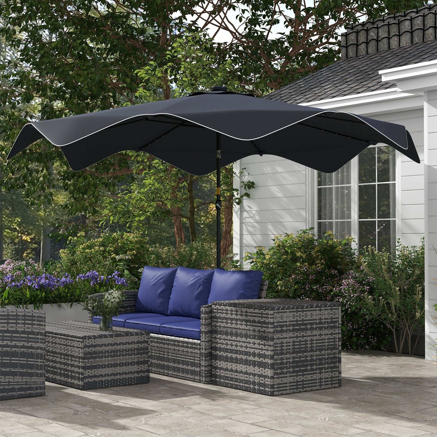 Outdoor patio set with blue cushions and a large black umbrella in a garden setting.