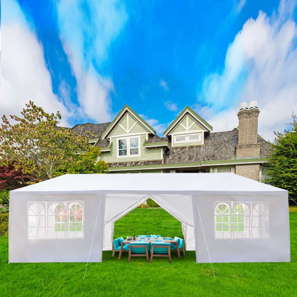White outdoor canopy tent set up on a grassy lawn with a house in the background