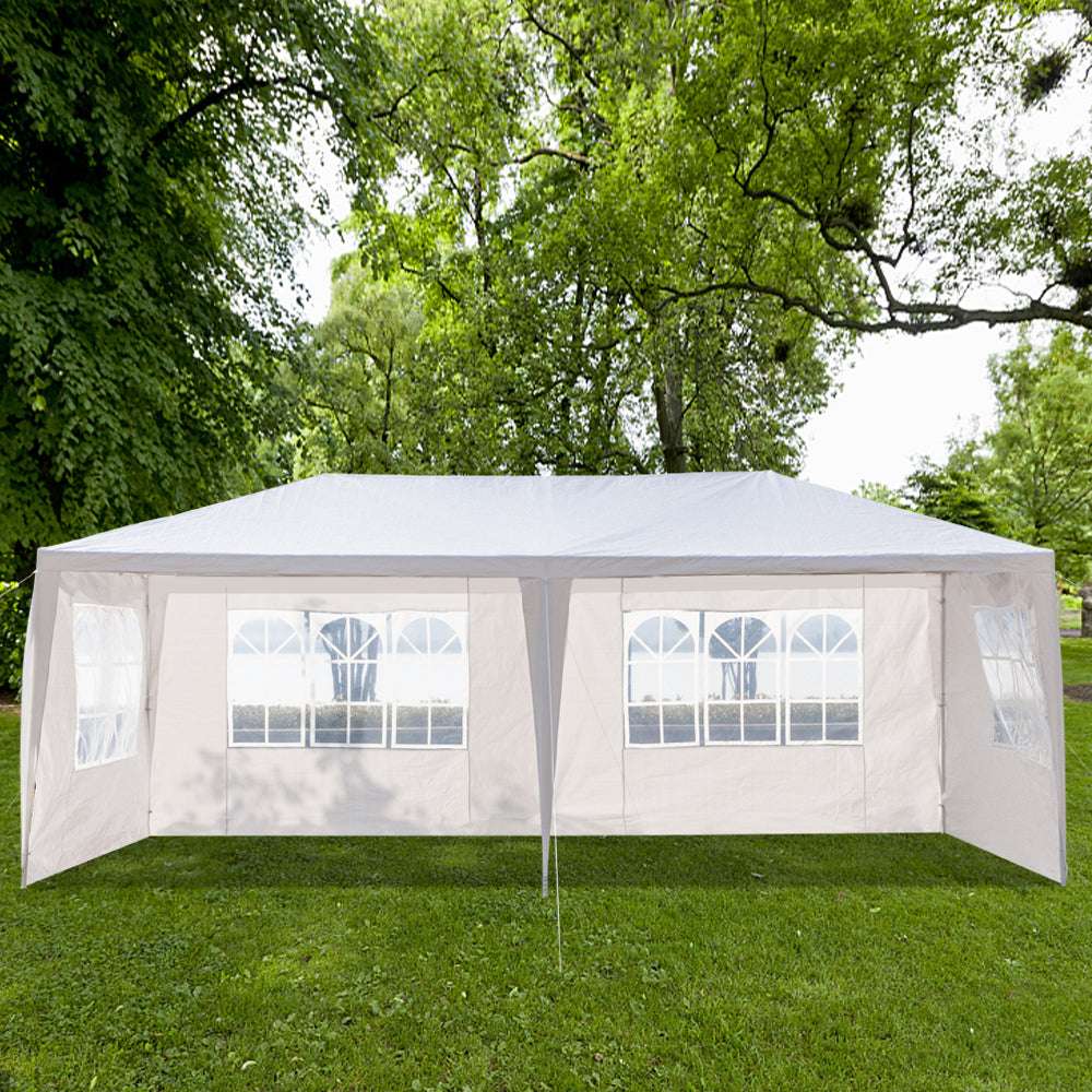 White outdoor canopy tent with windows on a grassy area with trees in the background