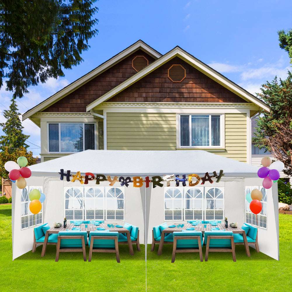 Outdoor birthday party setup with tables, chairs, and 'Happy Birthday' banner in front of a house.