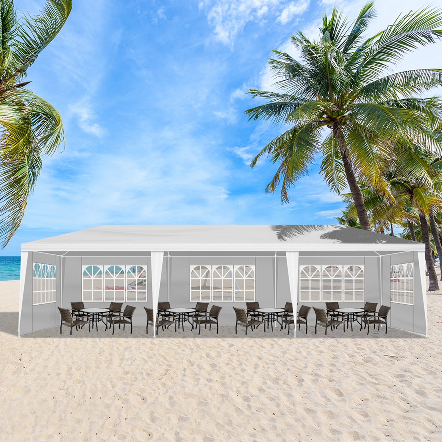 Outdoor event tent on a sandy beach with palm trees and clear blue sky.