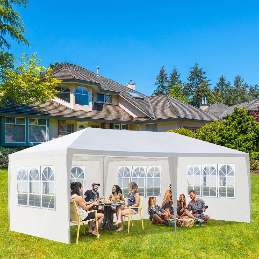 White outdoor canopy tent with people sitting inside on a sunny day.