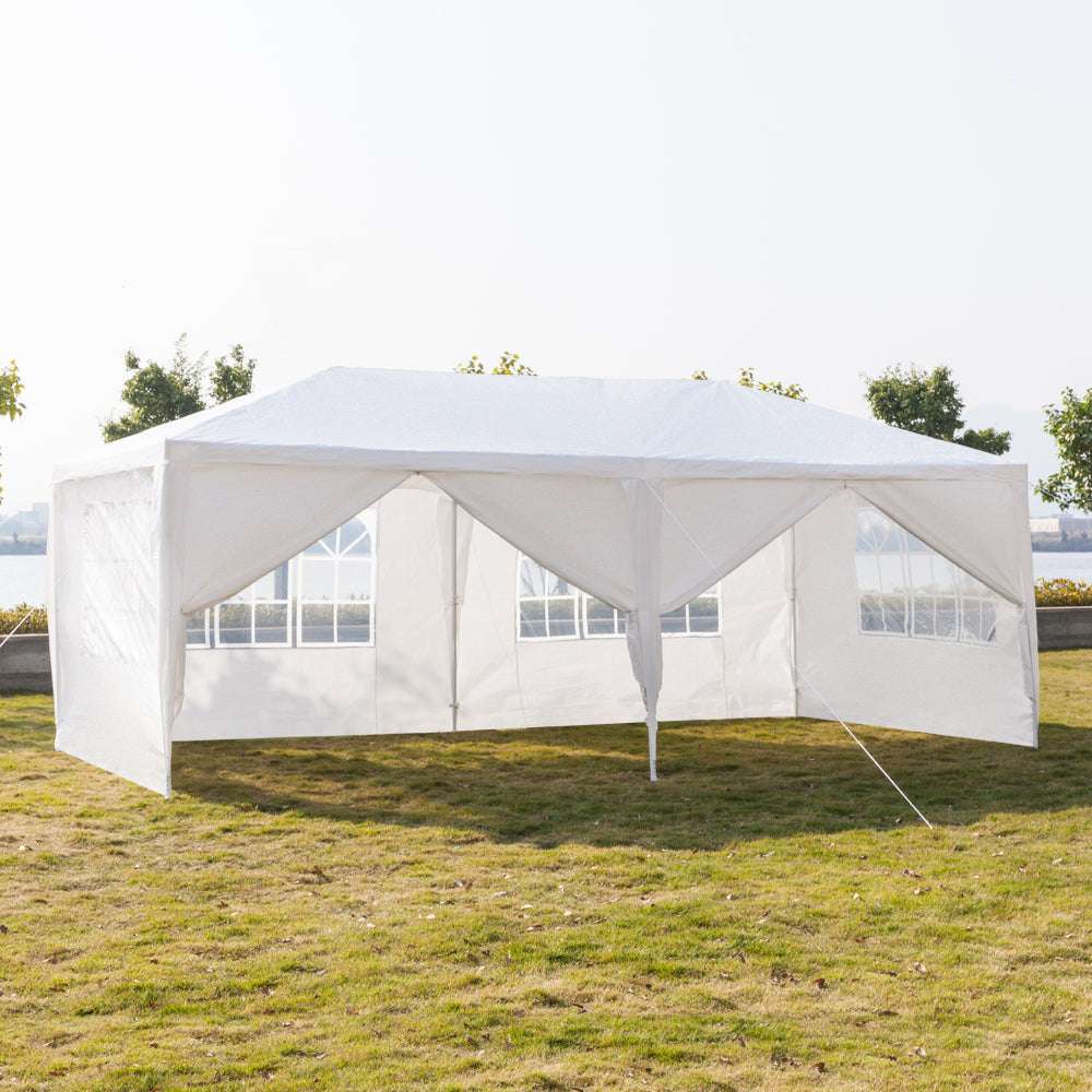 White outdoor canopy tent set up on grass with trees in the background