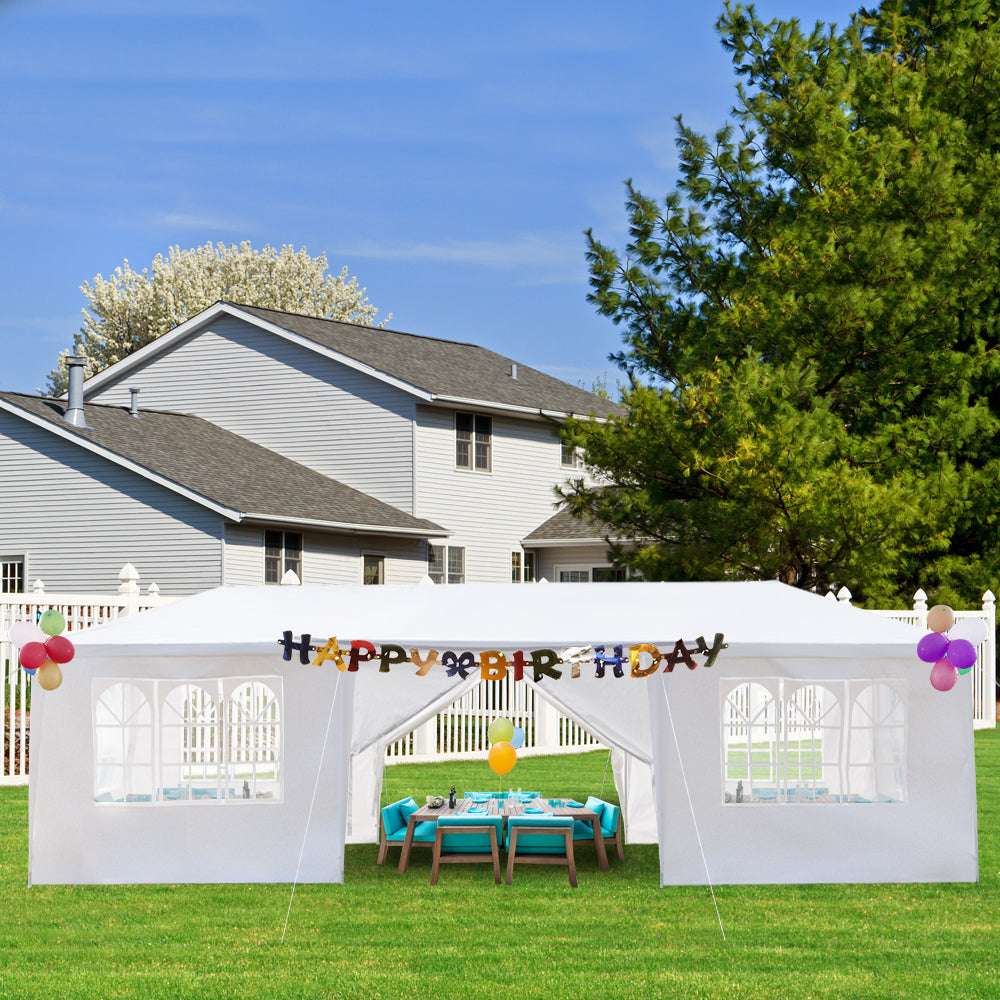 White outdoor canopy tent with 'Happy Birthday' banner in a backyard setting.