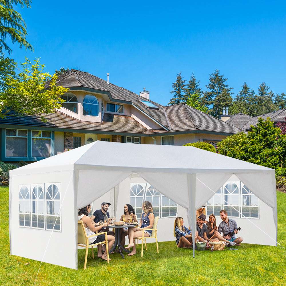 White outdoor canopy tent set up in a backyard with people sitting and socialising.