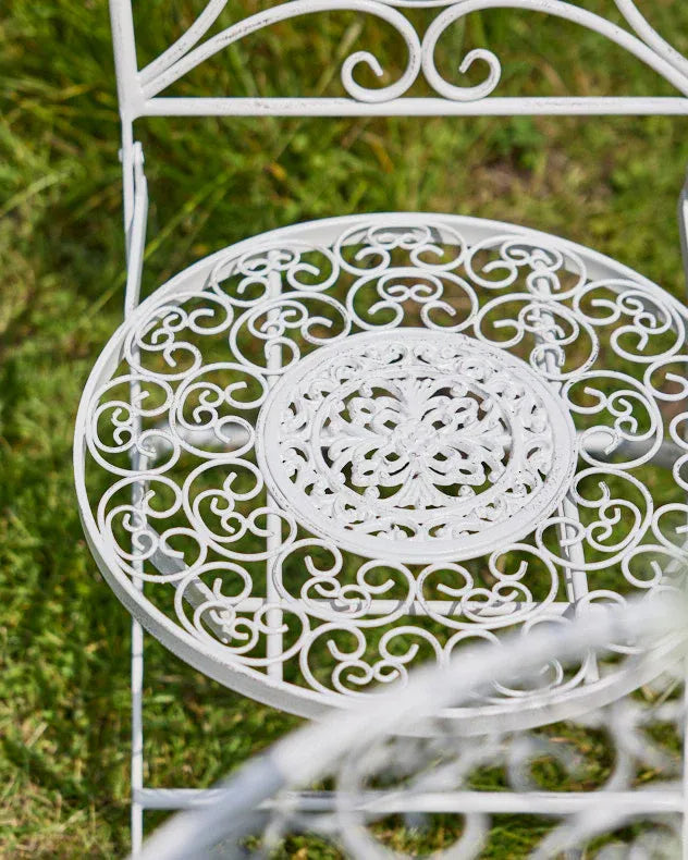 Decorative white metal chair part of the 3 piece bistro set with intricate patterns for garden comfort.