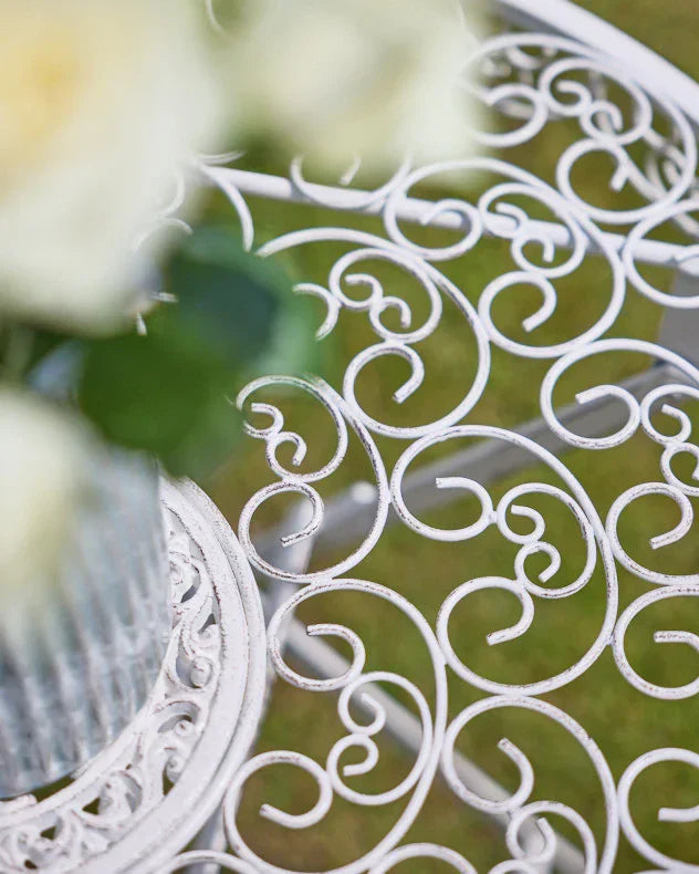 Decorative white metal bistro set with intricate patterns for luxury garden relaxation.