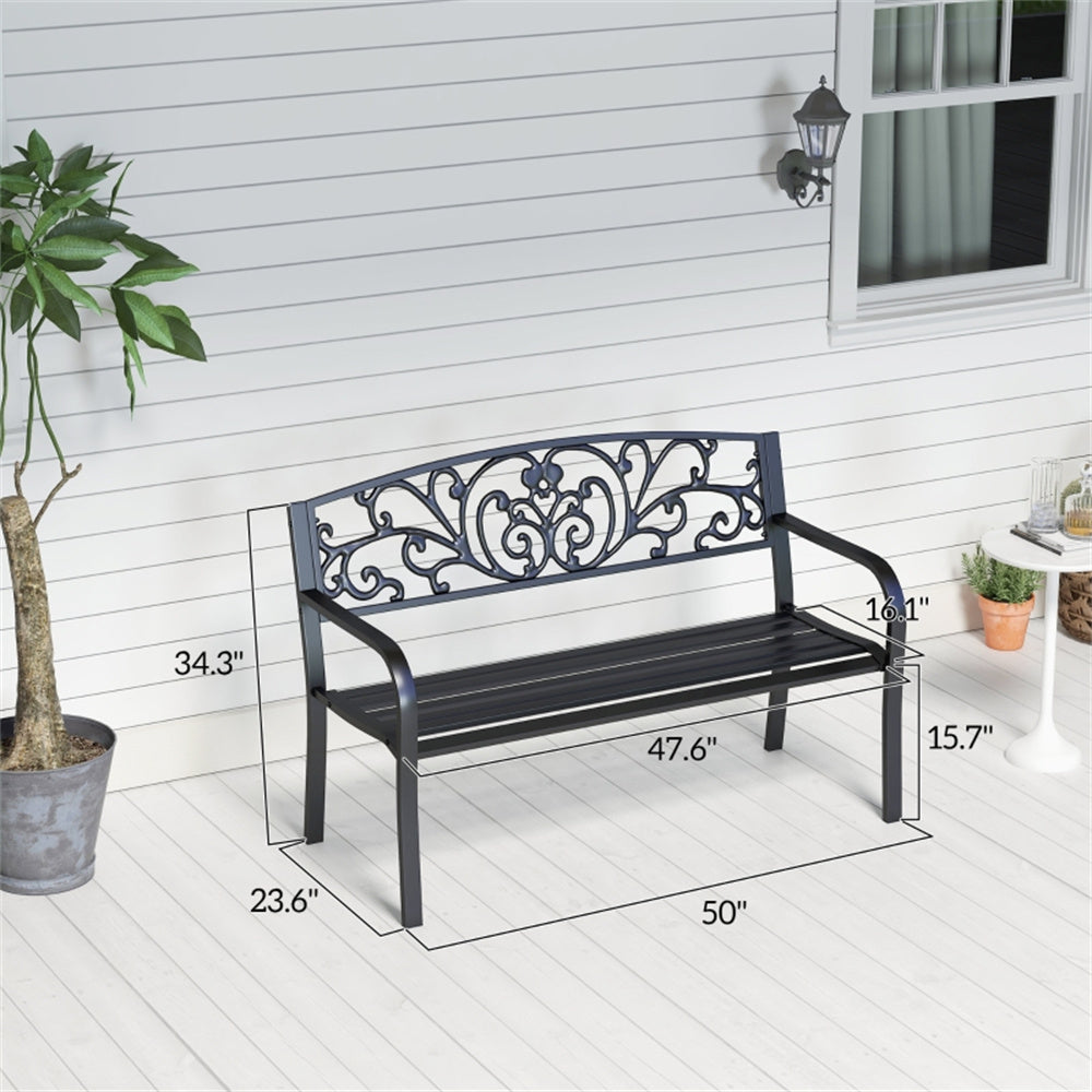 Black metal garden bench with decorative backrest on a white wooden deck, surrounded by plants.