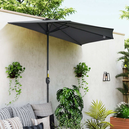 Black patio umbrella on a white wall with plants and outdoor furniture.