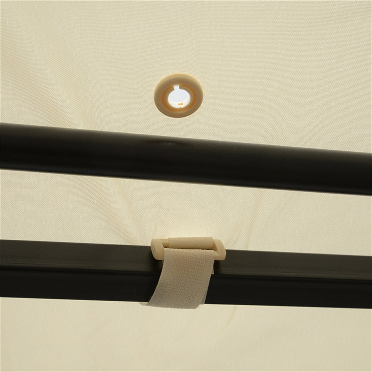 Close-up of a black metal rod with a beige strap and eyelet on a beige background