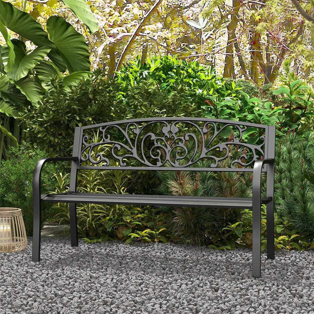 Decorative metal bench in a garden setting with lush greenery.