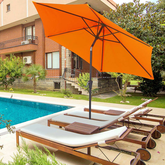 Orange patio umbrella over lounge chairs by a poolside with a house in the background