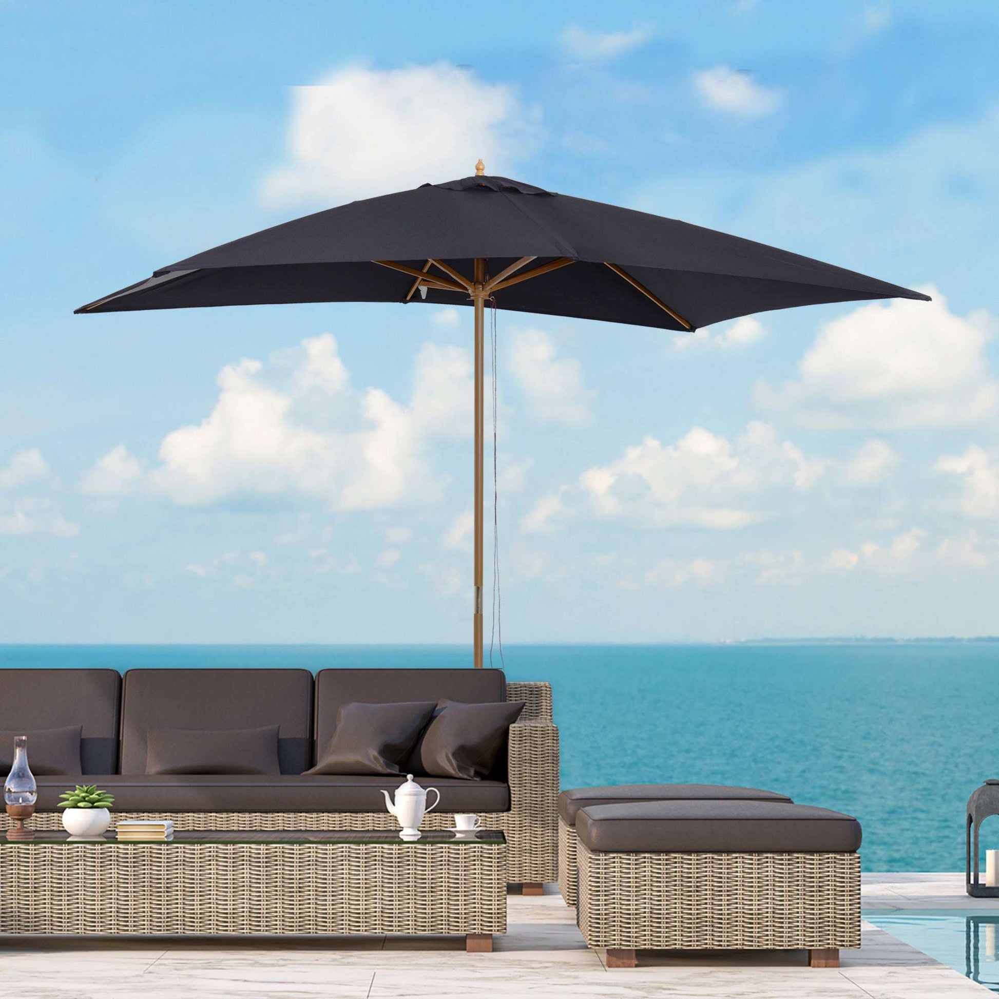 Outdoor patio set with a large black umbrella overlooking a blue ocean.