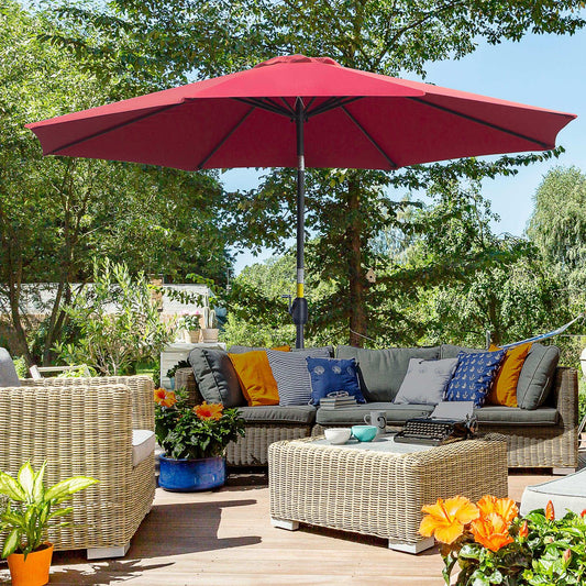 Outdoor patio setup with a red umbrella, grey sofa, and wicker furniture on a wooden deck.