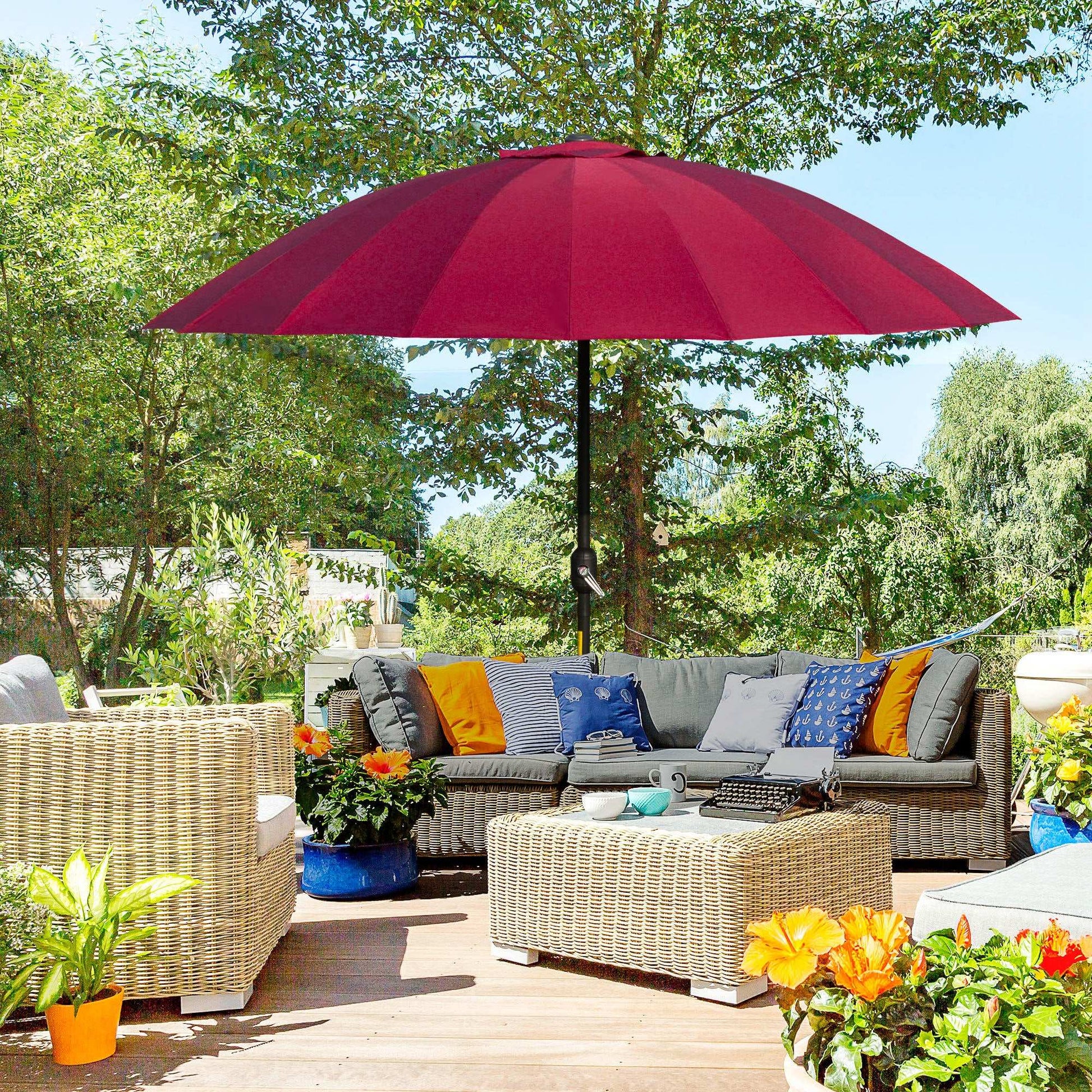 Red patio umbrella over an outdoor seating area with colourful cushions and plants.