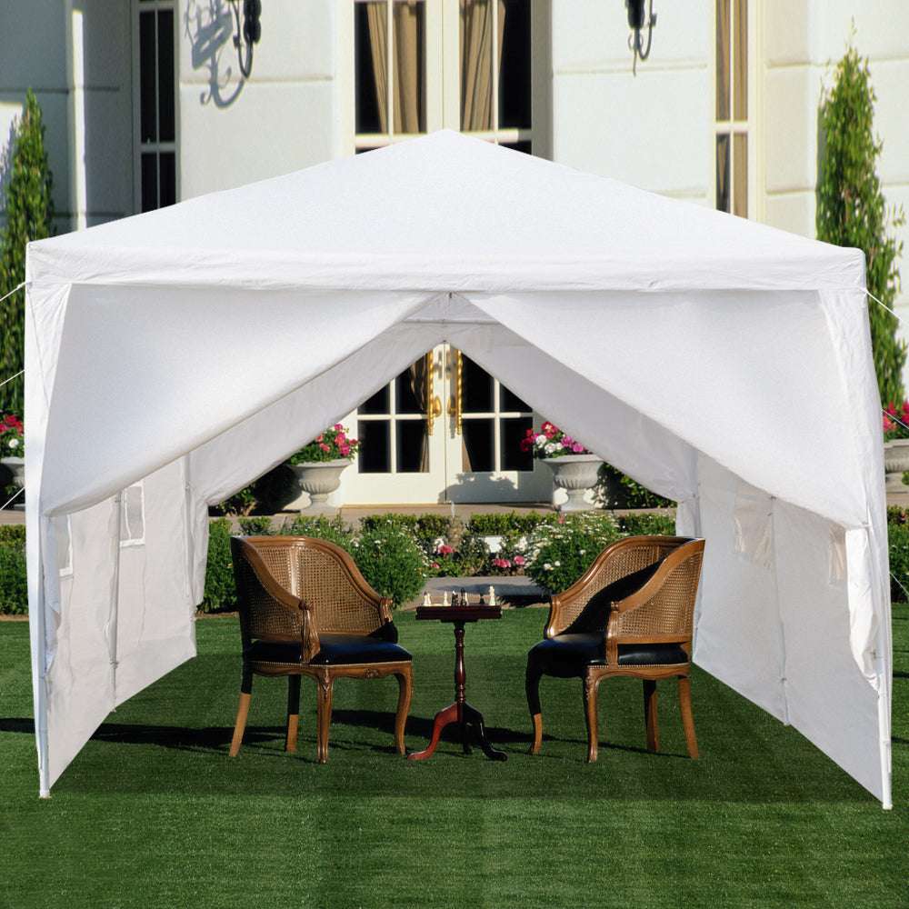 White outdoor canopy tent with chairs and a table underneath on a grassy area.