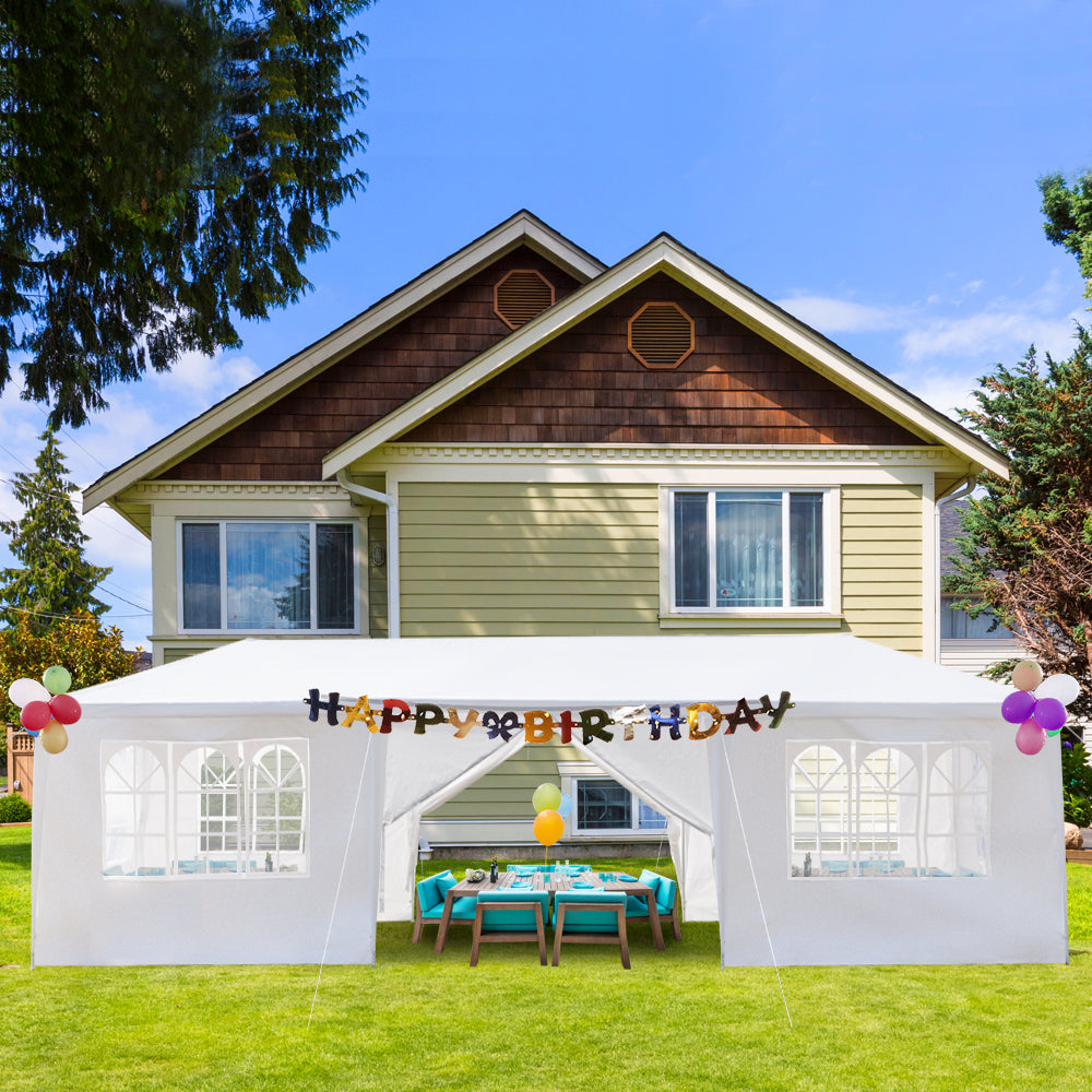 White outdoor canopy with 'Happy Birthday' banner set up in a backyard