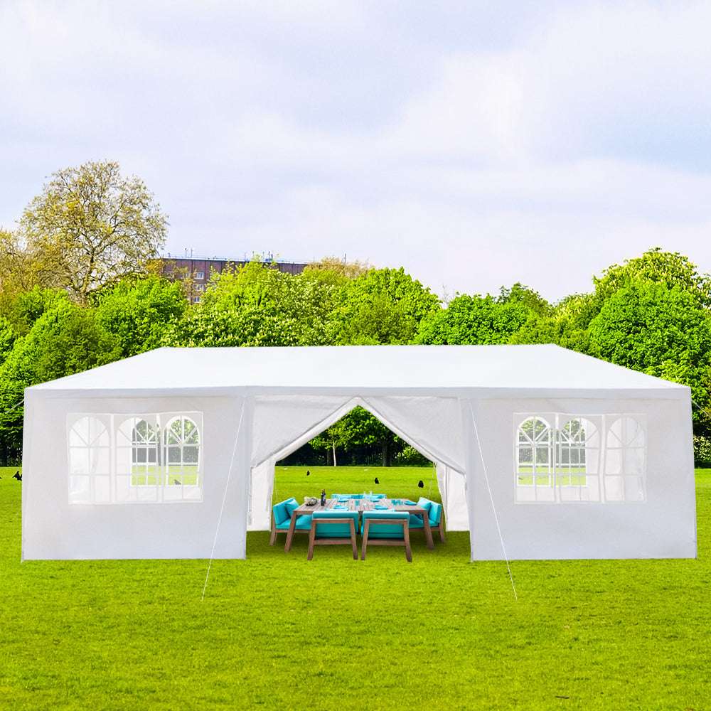 White outdoor canopy tent set up on grass with trees in the background