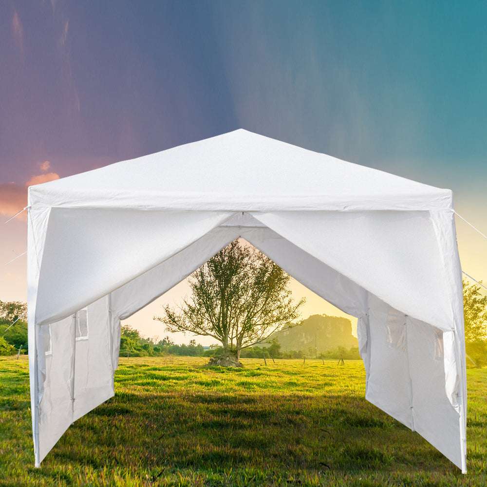 White outdoor canopy tent set up in a grassy field with a scenic background.