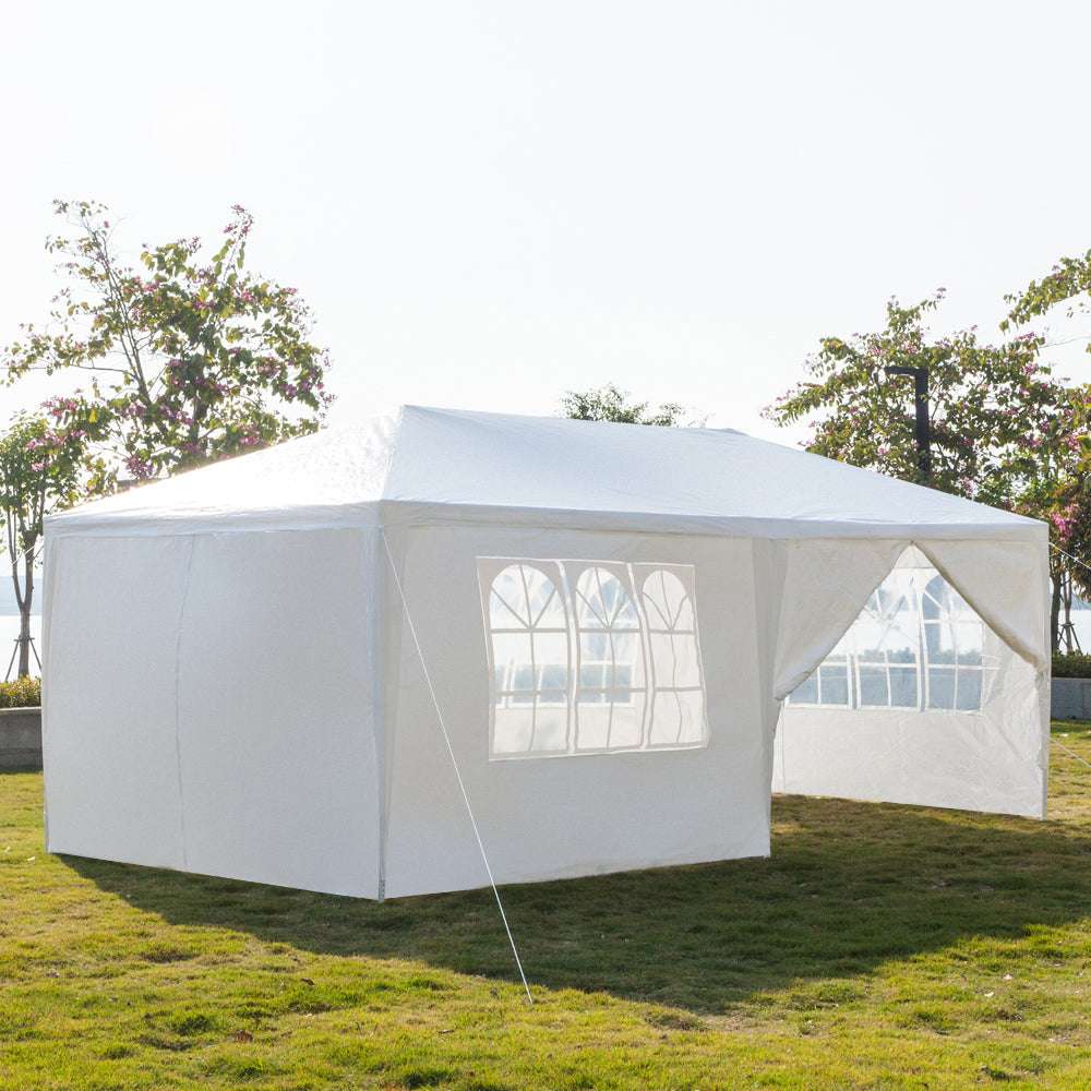 White outdoor canopy tent with windowed side panels with trees in the background